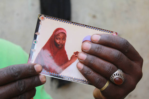 Seorang ibu menunjukkan foto putrinya yang diculik dalam peristiwa penculikan massal di Chibok, Nigeria, 12 April 2019. Aksi tersebut merupakan bagian dari peringatan lima tahun penculikan ratusan siswi oleh kelompok Boko Haram. Foto: Audu Marte/Agence France-Presse via Getty Images