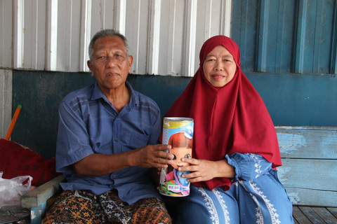 Pasangan suami istri pedagang gorengan di Kabupaten Kudus, Jawa Tengah menunjukkan kaleng tabungan di depan warungnya. Foto: Vega Maarijil Ula/kumparan