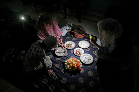Sebuah keluarga makan malam di rumah dengan penerangan senter ponsel selama pemadaman listrik di Islamabad, Pakistan, Rabu (15/4/2026). Foto: Aamir Qureshi/AFP