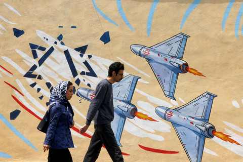 Sejumlah warga melintas di depan mural bernuansa anti-Amerika Serikat dan anti-Israel di Teheran pada Selasa, (21/4/2026). Foto: Atta Kenare/AFP