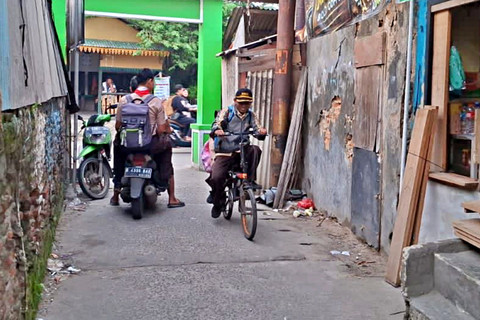 Abdul Aziz, guru yang tengah membonceng anaknya ke Sekolah MI Nurul Islam 1. Foto: Rayyan/Kumparan