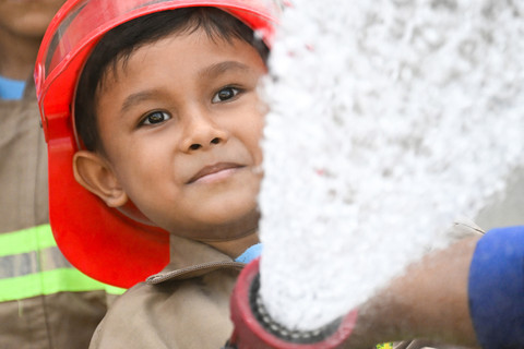 Seorang siswa taman kanak-kanak diperlihatkan cara menggunakan selang air oleh seorang petugas pemadam kebakaran di Banda Aceh, Kamis (23/4/2026). Foto: Chaideer Mahyuddin/AFP