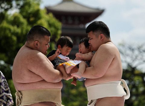 Pegulat sumo amatir menggendong bayi selama 'Nakizumo' atau kontes sumo bayi menangis di kuil Sensoji di Tokyo, Jepang, Sabtu (25/4/2026). Foto: Issei Kato/REUTERS