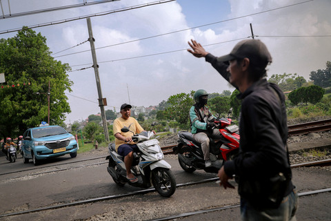 Arpin (40) menjaga pintu perlintasan kereta api sebidang di kawasan TPU Tanah Kusir, Jakarta Selatan, Kamis (30/4/2026). Foto: Jamal Ramadhan/kumparan