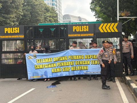 Polisi membentangkan spanduk menyambut kedatangan massa aksi di Patung Kuda, Monas, Jakarta, Sabtu (2/5/2026). Foto: Zamachsyari/kumparan