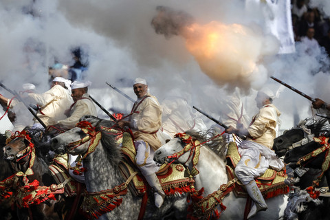 Para pria yang mengenakan pakaian tradisional menunggang kuda dan menembakkan senapan mereka selama pertunjukan berkuda Tbourida, atau Fantasia, di kota Bouznika, Maroko, Rabu (13/5/2026). Foto: ABDEL MAJID BZIOUAT/AFP