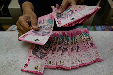 Petugas penukaran uang menghitung uang Rupiah di sebuah gerai penukaran mata uang di Jakarta (12/5/2026). Foto: Bay Ismoyo/AFP