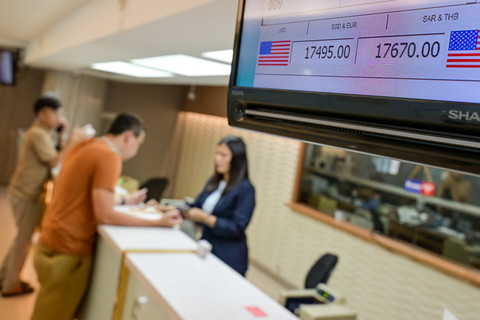 Layar monitor menampilkan kurs jual dan beli Rupiah terhadap dolar AS saat petugas melayani pelanggan di sebuah gerai penukaran mata uang di Jakarta (12/5/2026). Foto: Bay Ismoyo/AFP