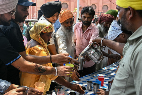 Sejumlah warga meminum air manis yang dibagikan oleh para sukarelawan di sepanjang jalan saat hari musim panas yang menyengat di Amritsar, Kamis (4/6/2026). Foto: NARINDER NANU/AFP
