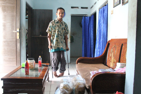 Abdul Muis (31) berjalan menggunakan tongkat penyangga. Foto: Vega Maarijil Ula/kumparan