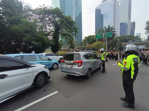 Polisi di Semanggi mengarahkan mobil ke Jalan Gatot Subroto karena jalan Jend Sudirman ditutup akibat demo mahasiswa di HI, Jumat (12/6/2026). Foto: Jamal Ramadhan/kumparan