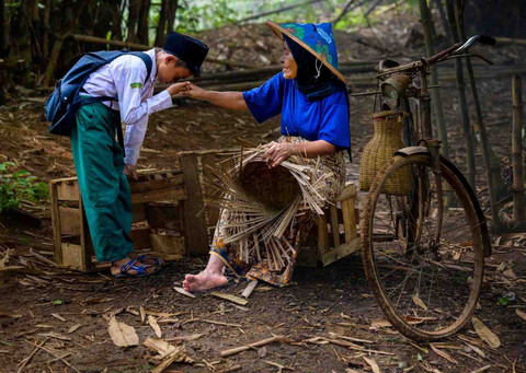 Seorang anak mencium tanganorang tua dalam sebuah pedesaan tradisional, yang menggambarkan rasa hormat budaya. Foto: Daniel lee/Pexels