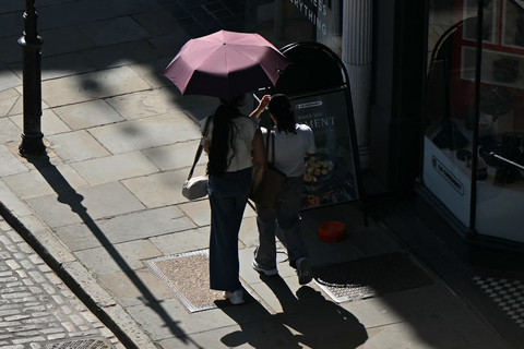 Sejumlah warga berteduh di bawah payung dari teriknya sengatan matahari di Guildford, Inggris, Kamis (25/6/2026). Foto: Justin Tallis/AFP
