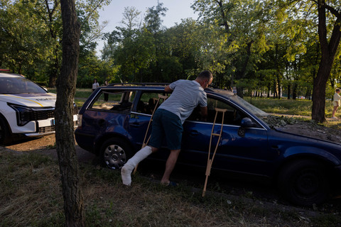 Seorang pria mengambil barang di sebuah mobil yang rusak di dekat bangunan tempat tinggal yang hancur setelah serangan udara Rusia di ibu kota Ukraina, Kyiv, Kamis (2/7/2026), di tengah invasi Rusia di Ukraina. Foto: TETIANA DZHAFAROVA/AFP