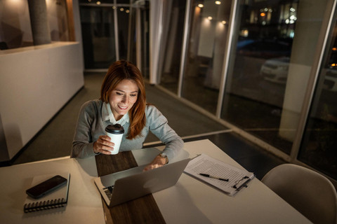 Seorang anak muda bekerja hingga larut malam ditemani laptop dan secangkir kopi. Foto ini merepresentasikan budaya hustle yang sering dikaitkan dengan produktivitas berlebihan dan tekanan untuk selalu sibuk. sumber: unsplash