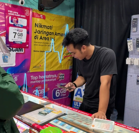 Pemilik konter hp Ultra Cell, Candra tengah melayani pelanggan di konter miliknya di kawasan Jatinegara, Jakarta Timur, Senin (7/7/2026). Foto: Widya Islamiati/kumparan