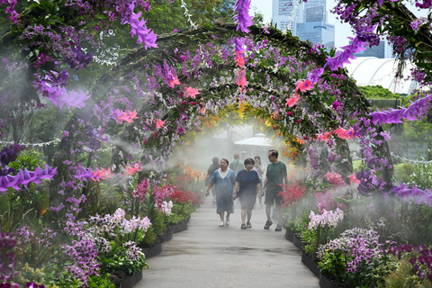 Pengunjung berjalan di sepanjang taman bunga yang ditata apik sambil disiram air selama Festival Taman Singapura ke-10 di Gardens by the Bay, Singapura, Selasa (7/7/2026). Foto: Roslan Rahman/AFP