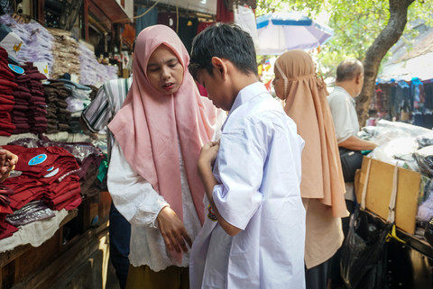 Orang tua bersama anak mencoba seragam sekolah di Pasar Jatinegara, Jakarta, Kamis (9/7/2026). Foto: Iqbal Firdaus/kumparan