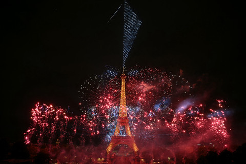 Kembang api menyala di sekitar Menara Eiffel selama pertunjukan kembang api dan drone yang dikoreografikan untuk merayakan Hari Bastille, di Paris, Prancis, Senin (13/7/2026). Foto: LOU BENOIST/AFP
