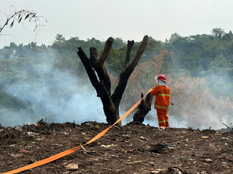 Petugas BPBD Kabupaten Bogor melakukan upaya pemadaman asap di lokasi penumpukan sampah di Cikeas, Bogor, Kamis (16/7). Foto: Nasywa Athifah/kumparan