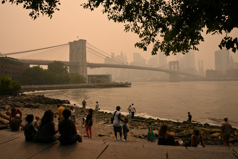 Sejumlah orang melihat ke arah Jembatan Brooklyn saat kabut asap akibat kebakaran hutan di Kanada memicu kondisi langit yang berkabut di New York, Amerika Serikat, Kamis (16/7/2026). Foto: Angela Weiss/AFP