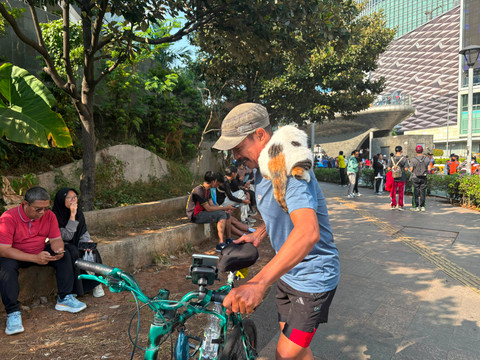 Warsito (54), pesepeda yang selalu menggendong kucingnya, Telon, saat berolahraga di CFD Bundaran HI, Jakarta Pusat, Minggu (26/7/2026). Foto: Nasywa Athifah/kumparan