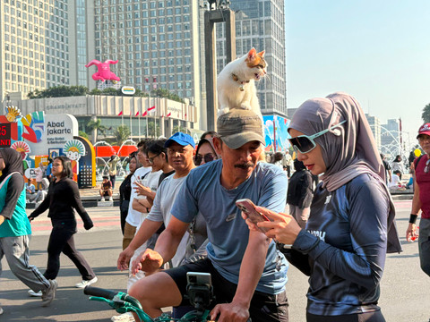 Warsito (54), pesepeda yang selalu menggendong kucingnya, Telon, saat berolahraga di CFD Bundaran HI, Jakarta Pusat, Minggu (26/7/2026). Foto: Nasywa Athifah/kumparan
