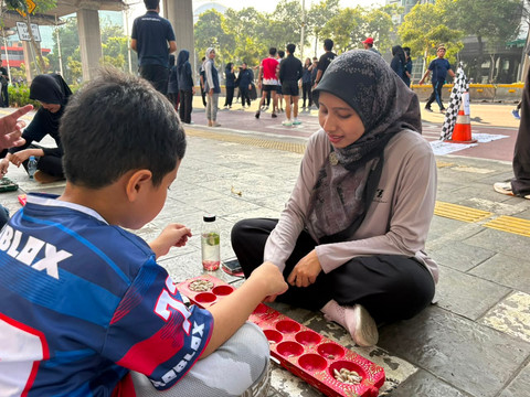 Adis (34) warga Depok, Jawa Barat,  saat bermain permainan tradisional di kawasan CFD Rasuna Said, Jakarta Selatan, Minggu (26/7/2026).  Foto: Nauval Pratama/kumparan