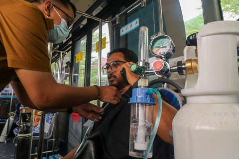 Petugas kesehatan membantu warga yang menerima oksigen dari bus kesehatan keliling yang dioperasikan oleh pemerintah kota Palangkaraya menyusul masalah pernapasan yang disebabkan oleh kebakaran lahan dan hutan pada Senin, 26 Oktober 2026. Foto: REINA / AFP
