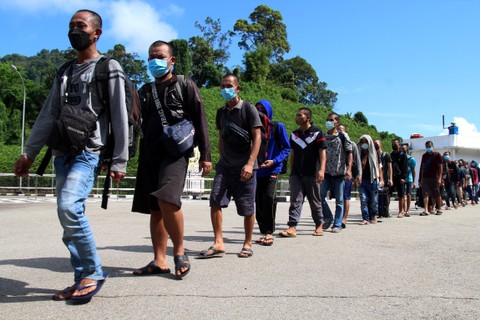 Sejumlah Pekerja Migran Indonesia Bermasalah (PMIB) berjalan memasuki Pos Lintas Batas Negara (PLBN) Entikong di Kabupaten Sanggau, Kalimantan Barat, Kamis (28/4/2022). Foto: Jessica Helena Wuysang/ANTARA FOTO