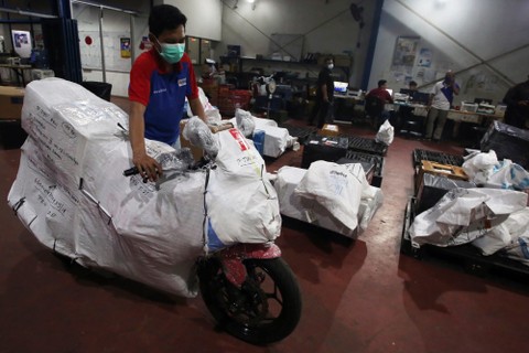 Pekerja mempersiapkan paket barang kiriman sepeda motor sebelum diberangkatkan dengan menggunakan pesawat di Gudang transit TIKI Kawasan Bandara Soekarno Hatta, Tangerang, Banten, Selasa (19/4/2022). Foto: Muhammad Iqbal/ANTARA FOTO