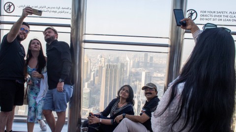 Pengunjung berfoto dengan latar belakang Kota Dubai di atas gedung Burj Khalifa di Uni Emirat Arab, Senin (14/3/2022). Foto: M Agung Rajasa/Antara Foto