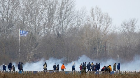 Para migran berjalan di dekat gas mata air di perbatasan Turki dan Yunani di Edirne, Turki. Foto: REUTERS / Huseyin Aldemir