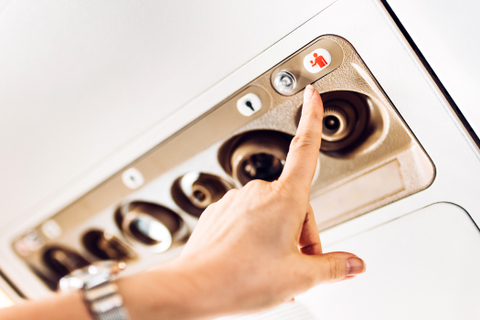 Seorang penumpang menekan tombol panggil pramugari di pesawat. Foto: Shutter Stock