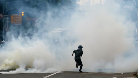 Massa berlari di tengah kepulan gas air mata, saat ricuh di aksi demo tolak Omnibus Law, di Jakarta, Selasa (13/10). Foto: Ajeng Dinar Ulfiana/REUTERS