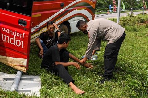 Personel polisi membersihkan luka dari penumpang sebuah mini bus yang bernopol E 7506 KC usai mengalami kecelakaan tunggal di kilometer 166 Tol Palimanan-CIkampek, Jawa Barat, Selasa (26/4/2022). Foto: M Risyal Hidayat/ANTARA FOTO
