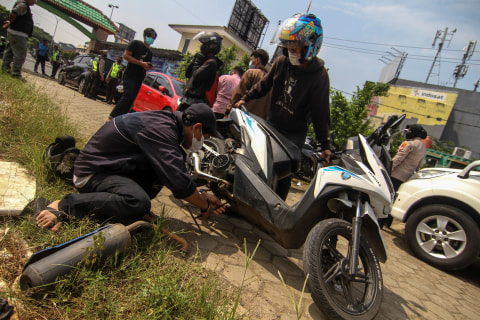 Pengendara mencopot knalpot bising usai terjaring razia yang digelar Satlantas Polres Metro Depok di Jalan Margonda, Depok, Jawa Barat, Jumat (19/3). Foto: Asprilla Dwi Adha/Antara Foto