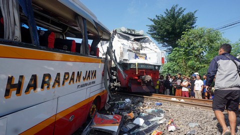 Warga melihat dari dekat kondisi bus dan lokomotif KA Rapih Dhoho yang rusak berat usai tabraka maut di perlintasan kereta api tanpa palang pintu di Desa Ketanon, Tulungagung, Jawa Timur, Minggu (27/2/2022). Foto: Deny Trisdanto/ANTARA FOTO