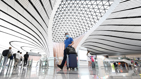 Seorang penumpang mendorong barang bawaannya ke area check-in di Bandara Internasional Daxing Beijing. Foto: WANG ZHAO / AFP