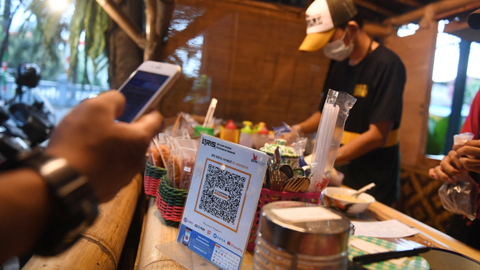 Pembeli membayar dengan metode scan Quick Response Code Indonesian Standard (QRIS) di warung KE Angkringan, Ampera, Jakarta, Jumat (30/7/2021). Foto: Akbar Nugroho Gumay/ANTARA FOTO
