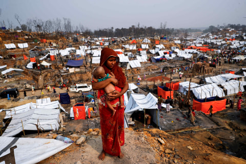 Pengungsi Rohingya terlihat mengendong anaknya di depan tenda darurat yang baru didirikan setelah kebakaran besar di Cox's Bazar, Bangladesh. Foto: Mohammad Ponir Hossain/Reuters