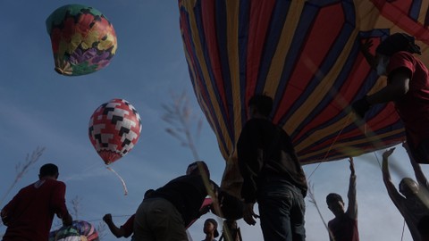 Sejumlah warga menerbangkan balon udara yang ditambatkan di tanah saat "Balloon Attraction Pekalongan 2022" di Lapangan Mataram, Kota Pekalongan, Jawa Tengah, Minggu (8/5/2022). Foto: Harviyan Perdana Putra/Antara Foto