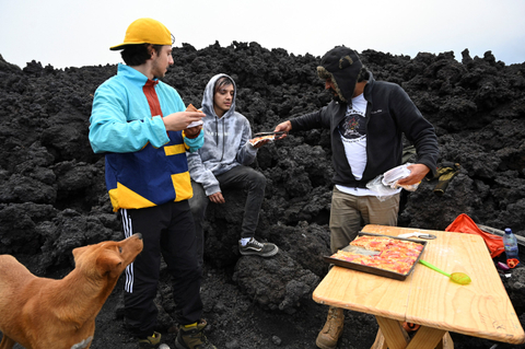 Chef David Garcia menyajikan pizza kepada wisatawan di gunung berapi Pacaya di Guatemala.   Foto: Johan Ordonez/AFP