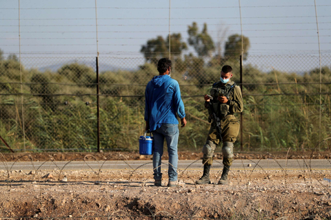 Tentara Israel memeriksa dokumen warga Palestina saat mereka menyeberang kembali ke Tepi Barat dari Israel melalui desa Muqeibila, Senin (6/9). Foto: Ammar Awad/Reuters