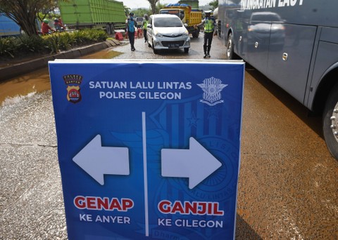 Anggota Satlantas Polres Cilegon memerintahkan putar arah kepada pengemudi kendaraan roda empat saat uji coba penerapan sistem ganjil-genap (gage) menuju Pantai Anyer, Sabtu (11/12/2021). Foto: Asep Fathulrahman/Antara Foto