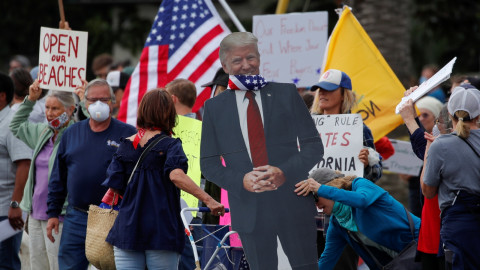 Warga membawa poster berbentuk Presiden AS Donald Trump saat melakukan demonstrasi di Encinitas, California, Amerika Serikat, Minggu (19/4). Foto: REUTERS/Mike Blake