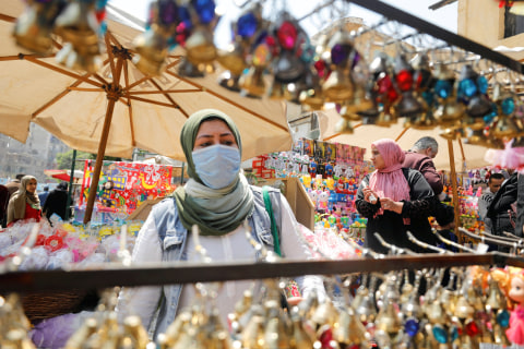Seorang wanita menggunakan masker membeli lentera 'Fanous' di sebuah kios di Kairo, Mesir. Foto: REUTERS / Mohamed Abd El Ghany