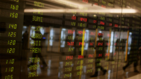 Karyawan melintas di depan layar pergerakan saham. Foto: ANTARA FOTO/Rivan Awal Lingga