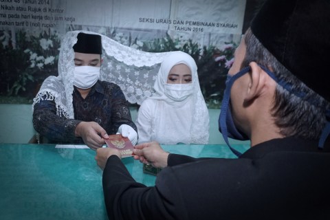 Pasangan pengantin Satrio dan Nuni menggunakan masker saat melaksanakan prosesi akad nikah di Kantor KUA Bekasi Utara.  Foto: Iqbal Firdaus/kumparan