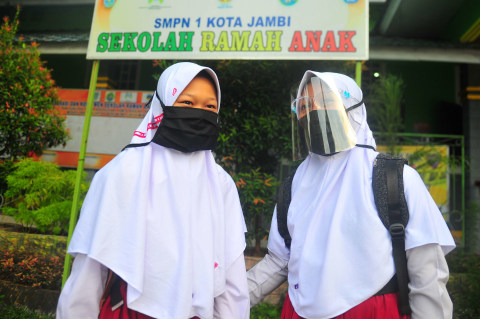 Siswi kelas VII SMPN 1 Kota Jambi mengenakan masker dan pelindung wajah sebelum memasuki kelas pada hari pertama sekolah Tahun Pelajaran 2020/2021 di Jambi. Foto: Wahdi Septiawan/ANTARA FOTO